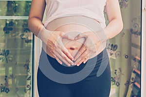 Pregnant Woman holding hand heart shape for baby in her tummy