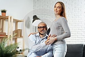 Pregnant woman holding a hand of her disabled husband sitting in a wheelchair