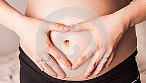 Pregnant Woman holding hands in a heart shape on