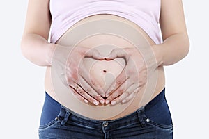 Pregnant woman holding hands in heart shape on belly, isolated o