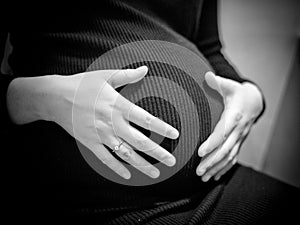 pregnant woman holding hands on her baby bump