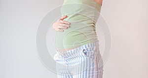 Pregnant woman holding hands on her belly. Belly of a pregnant woman on 16 week, 4 month. A woman is stroking her belly in the