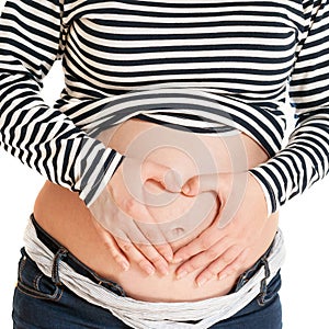 Pregnant woman holding hands on her belly making a heart symbol. Maternity concept.