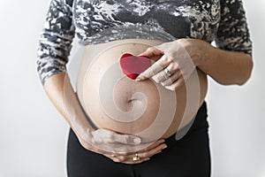 Pregnant woman holding a heart in front of her baby bump