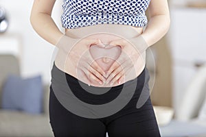 pregnant woman holding heart hands - maternity concept