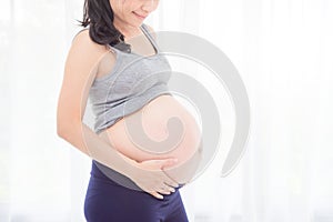 Pregnant woman,holding her belly in front of bright window