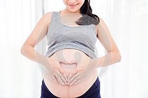 Pregnant woman,holding her belly in front of bright window