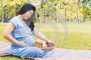 Pregnant woman holding her belly and healthy fruit which good for health.