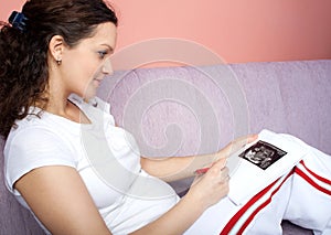 Pregnant woman holding her belly and writing notes