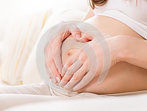 Pregnant woman holding her hands in a heart shape