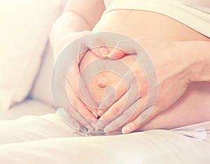 Pregnant woman holding her hands in a heart shape