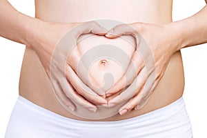 Pregnant woman holding her hands in a heart shape on belly.