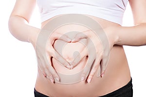 Pregnant Woman holding her hands in a heart shape on her baby bump. Pregnant Belly with fingers Heart symbol.