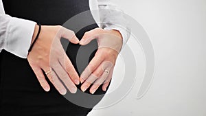 Pregnant Woman holding her hands in a heart shape on her baby bump. Pregnant Belly with fingers Heart symbol. Maternity