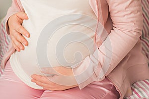Pregnant Woman holding her hands in a heart shape on her baby bump. Pregnant Belly with fingers Heart symbol. Maternity concept