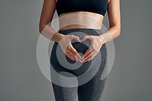 Pregnant woman holding her hands in a heart shape on her belly. Pregnant belly with fingers heart symbol. Maternity
