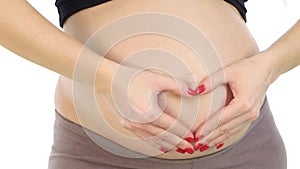 Pregnant woman holding her hands in a heart shape on her pregnant belly, white, closeup