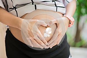 Pregnant Woman holding her hands in heart shape Pregnant Belly with fingers Heart symbol.