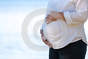 A pregnant woman holding her hands on her stomach.