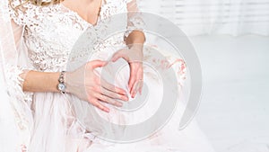 Pregnant woman holding her hands in the shape of heart on her be