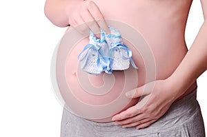 Pregnant woman holding her hands two baby shoes