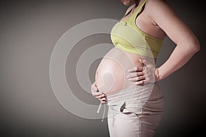 Pregnant woman is holding her stomach by her hand