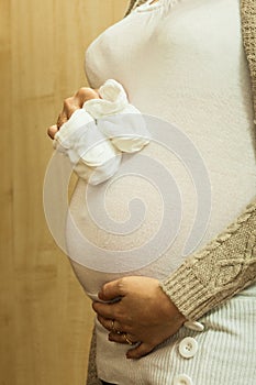 Pregnant woman holding little baby shoes