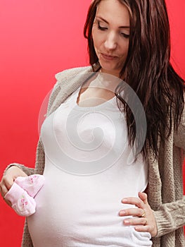 Pregnant woman holding little baby shoes