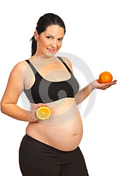 Pregnant woman holding orange fruit