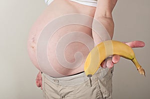 Pregnant woman holding out a banana