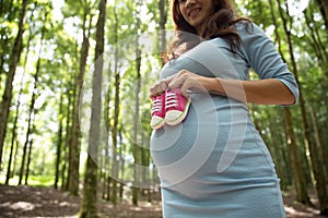 Pregnant woman holding a pair of pink sneakers toddler shoes