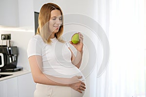 Pregnant woman holding pear. Healthy eating vegetables and fruit concept