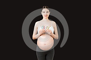 Pregnant woman holding pill blisters at colorful background with copy space. Medical problems during pregnancy concept