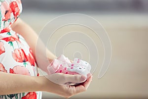 pregnant woman holding a set of newborn shoes