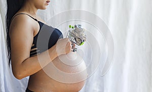 Pregnant women holding shopping cart with baby shoes. Pregnancy shopping item for children concept