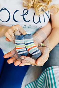 Pregnant woman holding small baby shoes