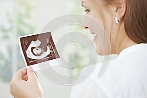 Pregnant woman holding sonogram photo