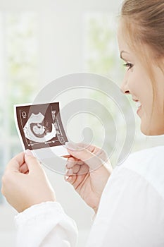 Pregnant woman holding sonogram photo