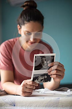 Pregnant woman holding a sonogram of her unborn baby