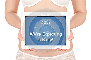 A pregnant woman is holding a tablet computer in f