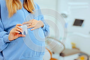 Pregnant Woman Holding a Tooth in a Dental Cabinet