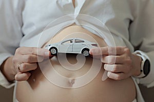 pregnant woman holding a toy car in her hands, the birth of a son