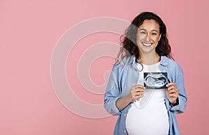 Pregnant woman holding ultrasound image of baby