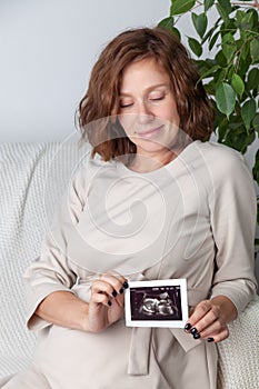 Pregnant woman holding ultrasound image. Concept of pregnancy, health care, gynecology, medicine. Young mother waiting