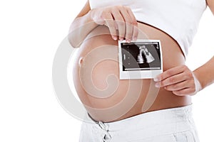 Pregnant woman holding ultrasound picture in front of belly