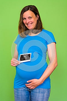 Pregnant woman holding ultrasound picture on her belly.
