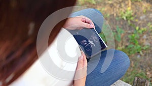 Pregnant woman holding ultrasound scan, photo or picture on the belly of her future daughter or son in the arms. Girl