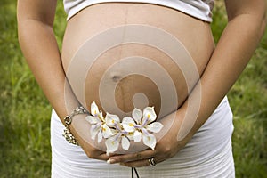 Pregnant woman holding white flowers in her hands