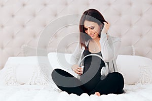 Pregnant Woman Holding Wireless Headphone on Her Belly