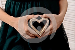 Pregnant woman holding a wooden heart in her hands